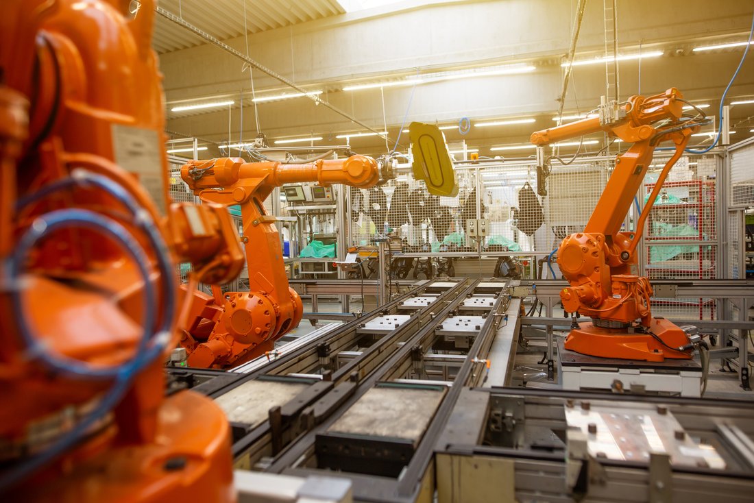 In der Fabrik: Orange Roboterarme am Arbeitsplatz
